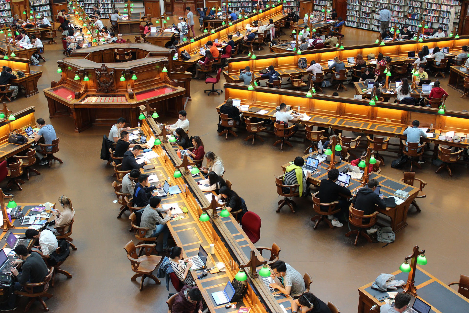 Old-style library filled with people sat at desks poring over books