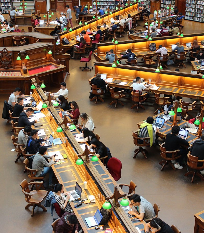 Old-style library filled with people sat at desks poring over books