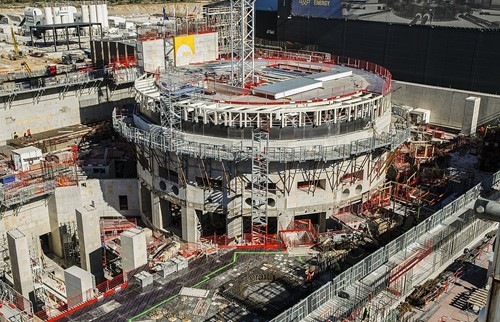 Aerial image showing a round concrete structure being built, covered in scaffolding