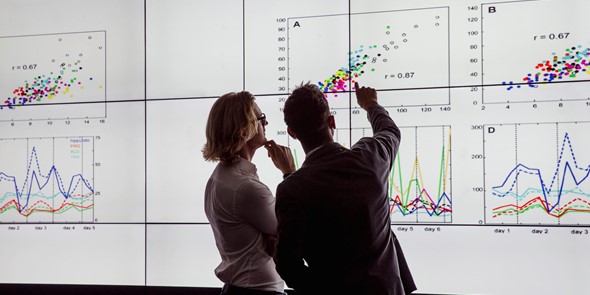 Woman and man in business clothes pointing at graphs