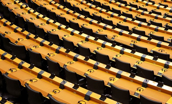 Rows of empty seats from a parliament hemicycle with headphones on desks and electronic voting equipment fitted