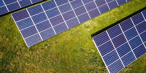 Aerial photograph of solar panels in a field of green grass